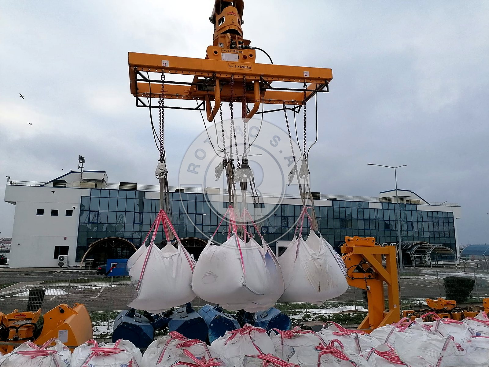 Patru big bags ridicați deodată cu spreaderul macaralei Mantsinen, deasupra lotului de pe cheu